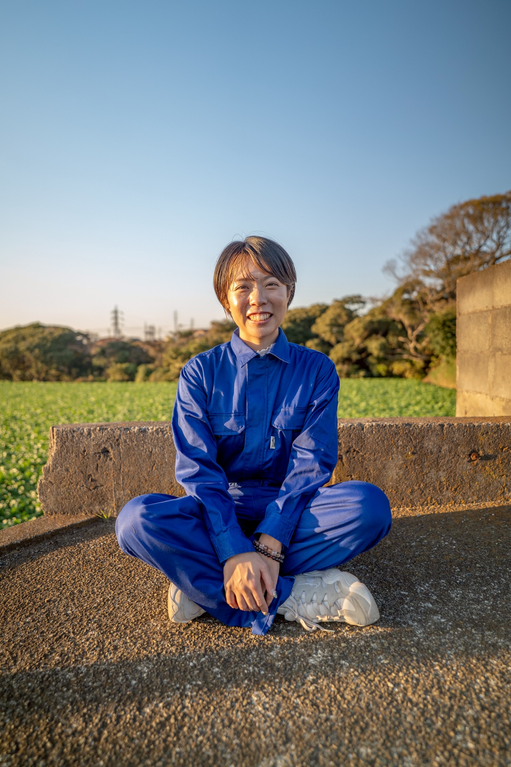 青い作業着で現場に立つ空き家娘