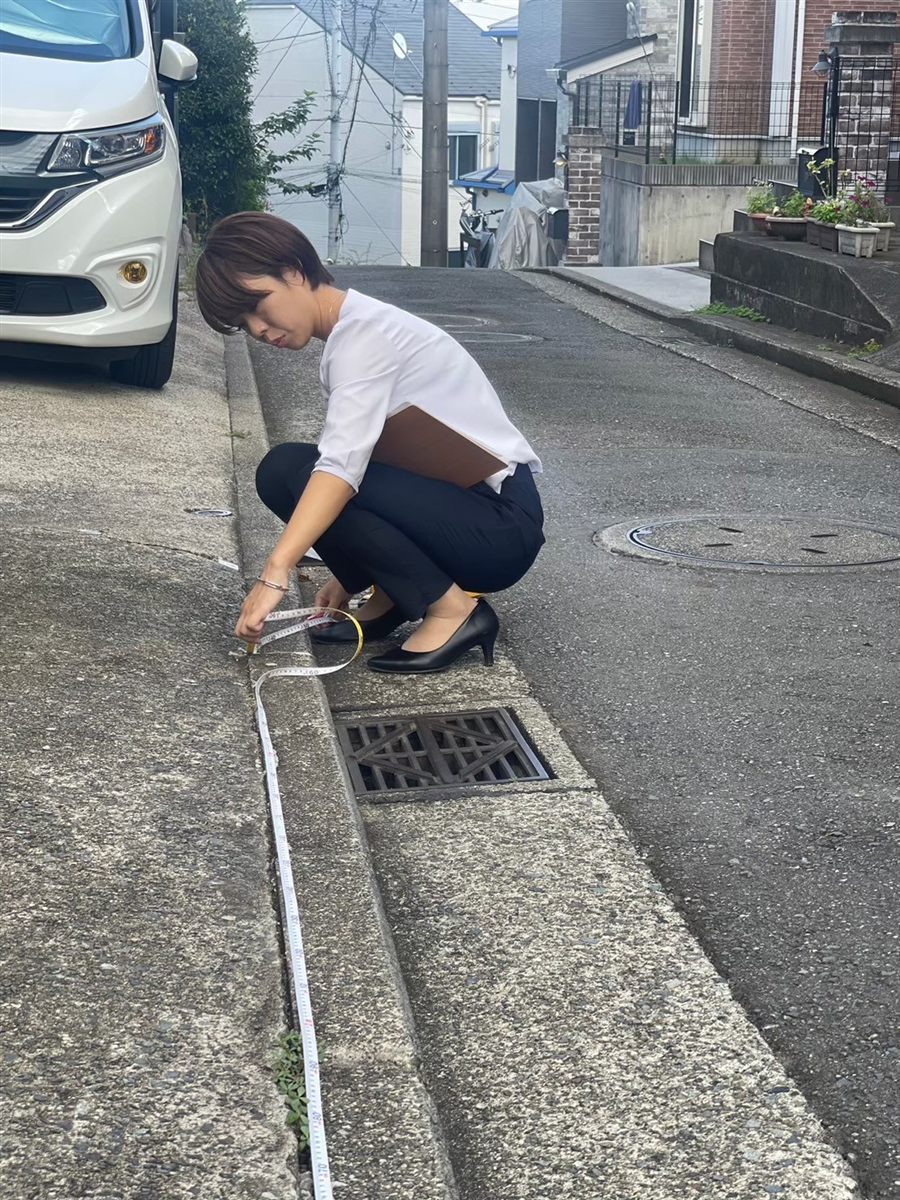 現場の道路脇でメジャーを使い、寸法を測る中村理沙